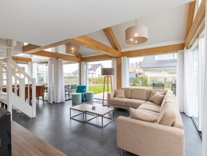 Ein geräumiger Wohnbereich mit einer Couch, einem Couchtisch und einer Treppe, die zu einer oberen Etage führt.