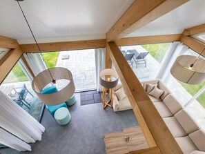 Ein modernes Interieur mit Holzboden, einer Couch, zwei Pendelleuchten und Blick auf die Terrasse.