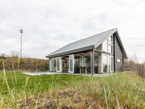 A modern house with a large glass facade, a sloped roof, and a visible outdoor seating area. - DuinZilver B by Interhome (Renesse)