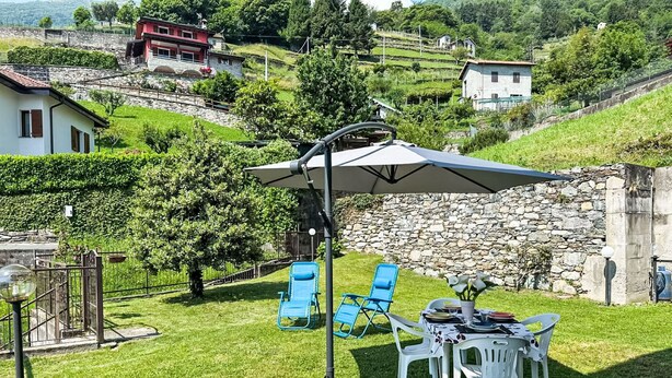 En terrasse med et bord, stole og en stor parasol.