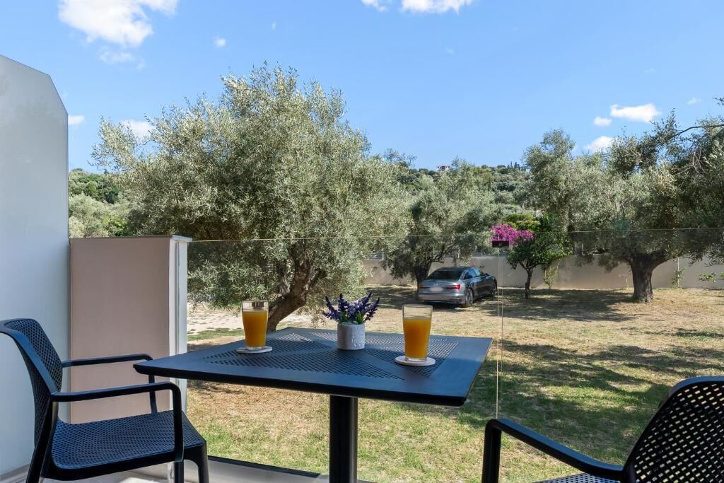 Ein Balkon mit Tisch, zwei Stühlen und zwei Gläsern Orangensaft.