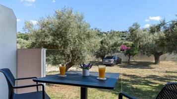 Ein Balkon mit Tisch, zwei Stühlen und zwei Gläsern Orangensaft.