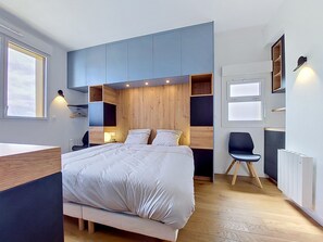 A modern bedroom with a bed, built-in shelving, a chair, and a desk. - Les Pieds dans l'Eau by Interhome (Roscoff)