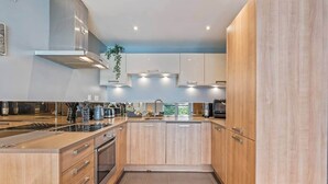 Eine moderne Küche mit Holzschränken, Edelstahlgeräten und einer Kochinsel.