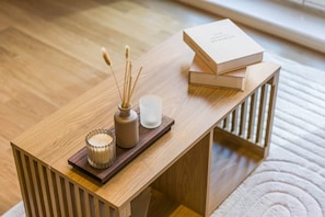 Una mesa de madera con una vela, difusor de cañas y un vaso de agua.