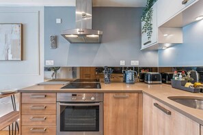 Una cocina moderna con horno empotrado, campana de acero inoxidable y armarios de madera.