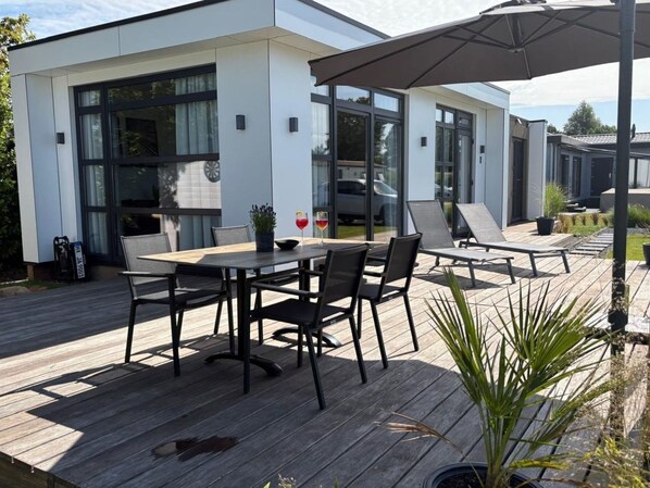 Un patio moderno al aire libre con una mesa de comedor, sillas y zonas de descanso.