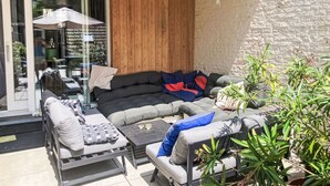 Een terras met een zithoek, een tafel en potplanten.