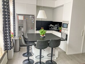 Une cuisine moderne dotée d’un îlot central, de tabourets de bar, d’un réfrigérateur et d’un four à micro-ondes.