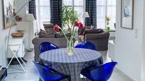 Een moderne woonkamer met een ronde tafel, blauwe stoelen, een bank en een potplant.