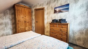 A bedroom with two beds, a wooden wardrobe, a dresser, and a poster on the wall. - Apartment Fecht by Interhome (Marienhafe)