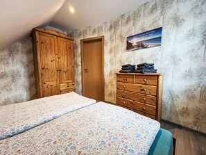 A bedroom with two beds, a wooden wardrobe, a dresser, and a poster on the wall. - Apartment Fecht by Interhome (Marienhafe)