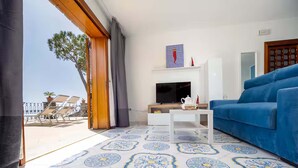 Una sala de estar con un sofá azul, un televisor y un piso estampado.