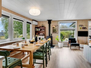 A modern kitchen with a dining area, large windows, a fireplace, and a TV mounted on the wall. - "Brunetta" - 200m to the fjord by Interhome (Øster Assels)