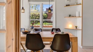 Un comedor con una mesa de madera, sillas negras y una ventana que da a zonas verdes.