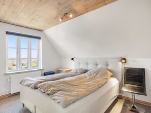 Et soveværelse med seng, sengebord, lampe og et vindue.