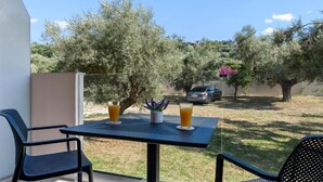 Un balcone con un tavolo, due sedie e due bicchieri di succo d'arancia.