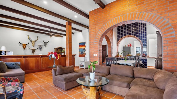 A spacious living area with a large sectional sofa, a glass coffee table, and a brick fireplace. - Private Boutique Hotel, Groups Up to 48 Guests (Puerto Vallarta)