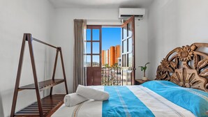 A hotel room with a bed, a wooden swing, a view of buildings, and an air conditioning unit. - Private Boutique Hotel, Groups Up to 48 Guests (Puerto Vallarta)