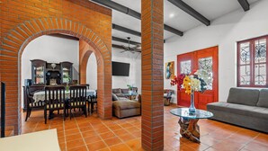 A spacious living area with a dining set, a sofa, and a TV mounted on the wall. - Private Boutique Hotel, Groups Up to 48 Guests (Puerto Vallarta)