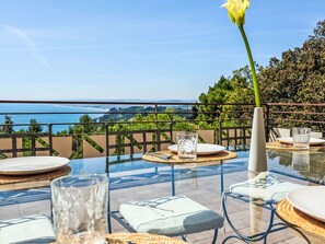 A glass table with a view of the sea, outdoor seating, and a vase with a flower. - Vacation home Sole by Interhome (Ancona)