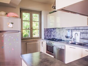 Een moderne keuken met een koelkast, fornuis, vaatwasser en raam met zonwering.