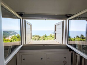 Ein Zimmer mit großem Fenster und Meer- und Grünblick.