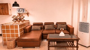 A living room with a brown leather sofa, a glass coffee table, a wicker basket, and a wall-mounted wine rack. - PhayaThai Autumn Hideaway • 2 Queen Beds • Vintage Kitchen (Krung Thep Maha Nakhon)
