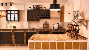 A modern kitchen with dark cabinets, a large island, and a hanging light fixture. - PhayaThai Autumn Hideaway • 2 Queen Beds • Vintage Kitchen (Krung Thep Maha Nakhon)