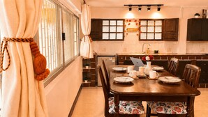 A dining area with a wooden table, chairs, and a laptop. - PhayaThai Autumn Hideaway • 2 Queen Beds • Vintage Kitchen (Krung Thep Maha Nakhon)