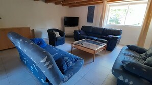 Ein Wohnzimmer mit einer Couch, einem Couchtisch, einem Fernseher und einem Fenster.