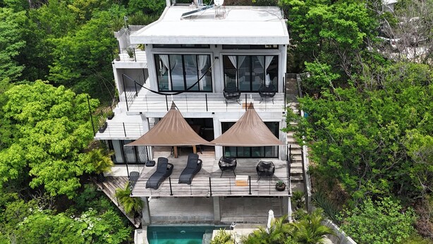 Una casa moderna con piscina, ventanas amplias y mobiliario exterior.
