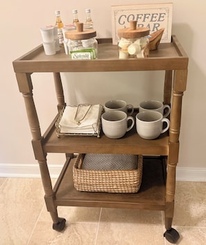 Una barra de café de madera con frascos, tazas y un letrero.