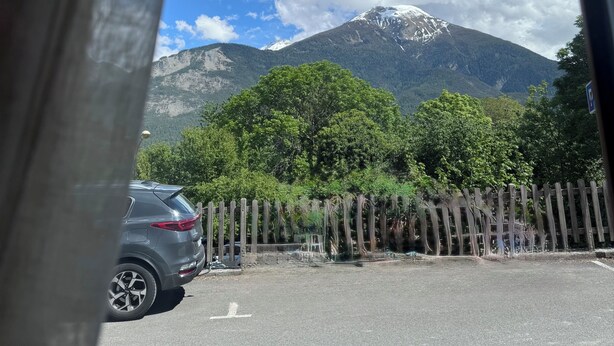 A mountain view through a window with a parked car and a wooden fence. - Cosy apartment under vaulted ceiling-6 people- Le Secret d'Adèle (Châteauroux-les-Alpes)
