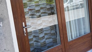 A wooden door with a glass panel reflecting a mountain and a vehicle. - Cosy apartment under vaulted ceiling-6 people- Le Secret d'Adèle (Châteauroux-les-Alpes)