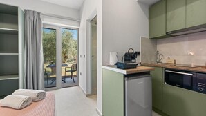 Ein modernes Zimmer mit einem Bett, einer kleinen Küchenzeile und einer Glastür zum Außenbereich.