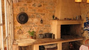 A rustic kitchen with a stone wall, a large pot, a hanging lantern, and a fireplace. - Bastide Saint-Martin (Cotignac)
