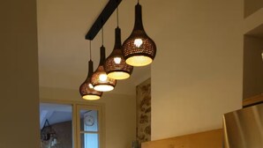 A modern kitchen with a dishwasher, oven, and refrigerator, wooden cabinets, and hanging pendant lights. - Bastide Saint-Martin (Cotignac)