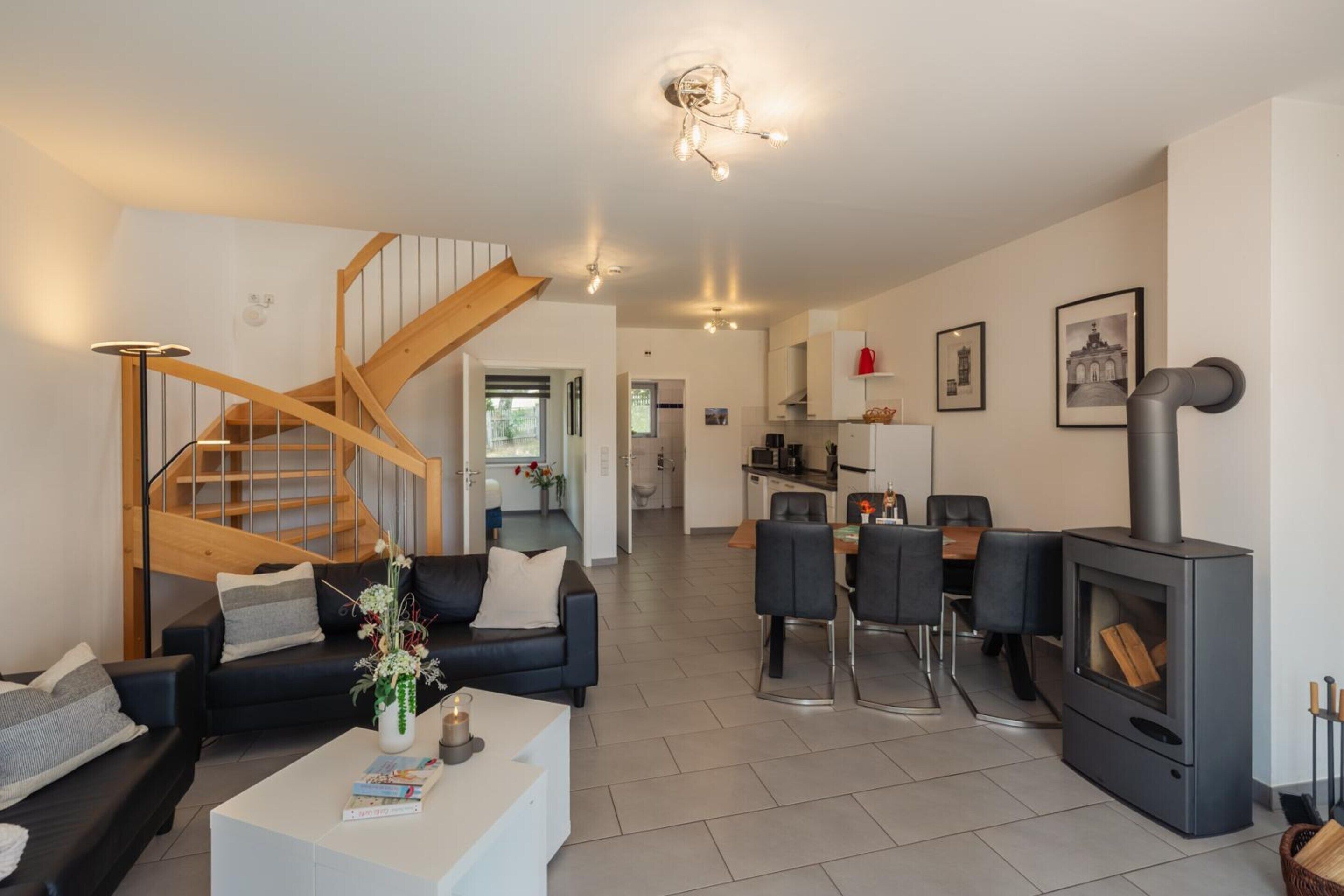 Una sala de estar moderna con una escalera, un comedor y una cocina.