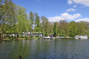 A lakeside property with docked boats, a house with a green roof, and trees surrounding the area. - Ferienwohnung mit Blick auf den Glindower See (Werder (Havel))