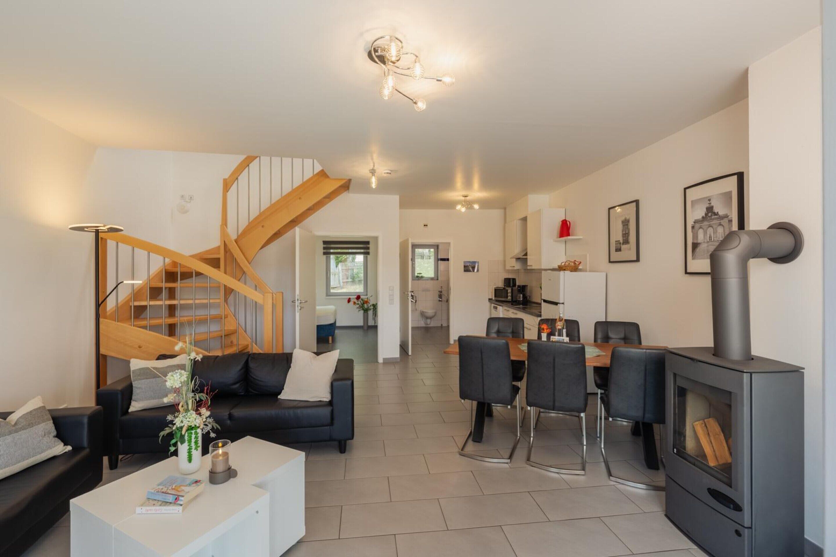 Un salon moderne avec un escalier, un coin repas et une cuisine.