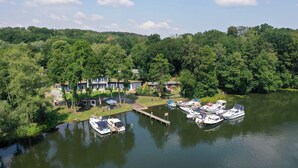 A lakeside property with a dock, boats, and a large house surrounded by dense forest. - Ferienwohnung mit Blick auf den Glindower See (Werder (Havel))