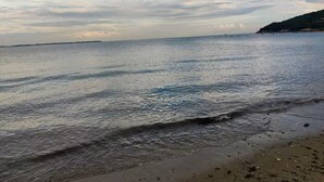 Ein Strand mit ruhigem Wasser und einer entfernten Küstenlinie.