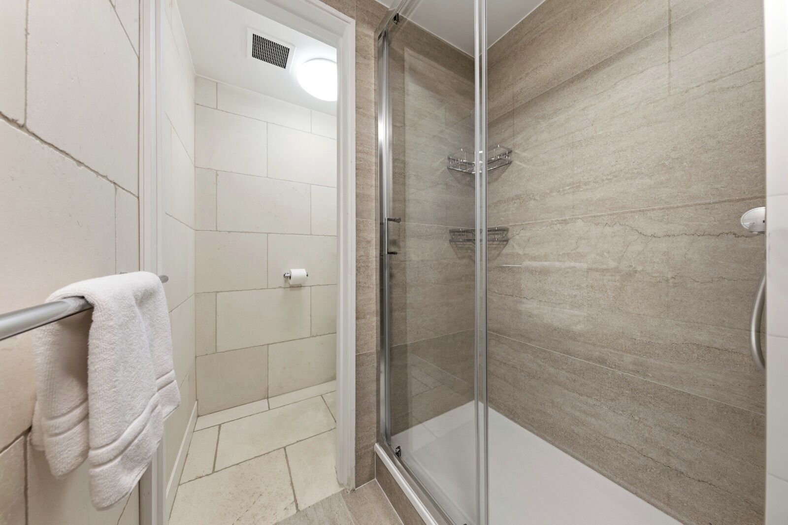 Une salle de bain avec une douche à parois de verre, un porte-serviettes et un support à papier toilette.