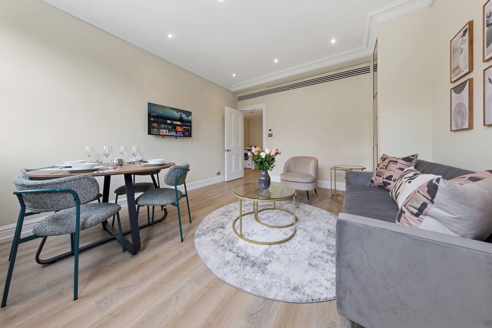 A modern living room with a sofa, a coffee table, and a dining area with chairs and a table set for a meal.