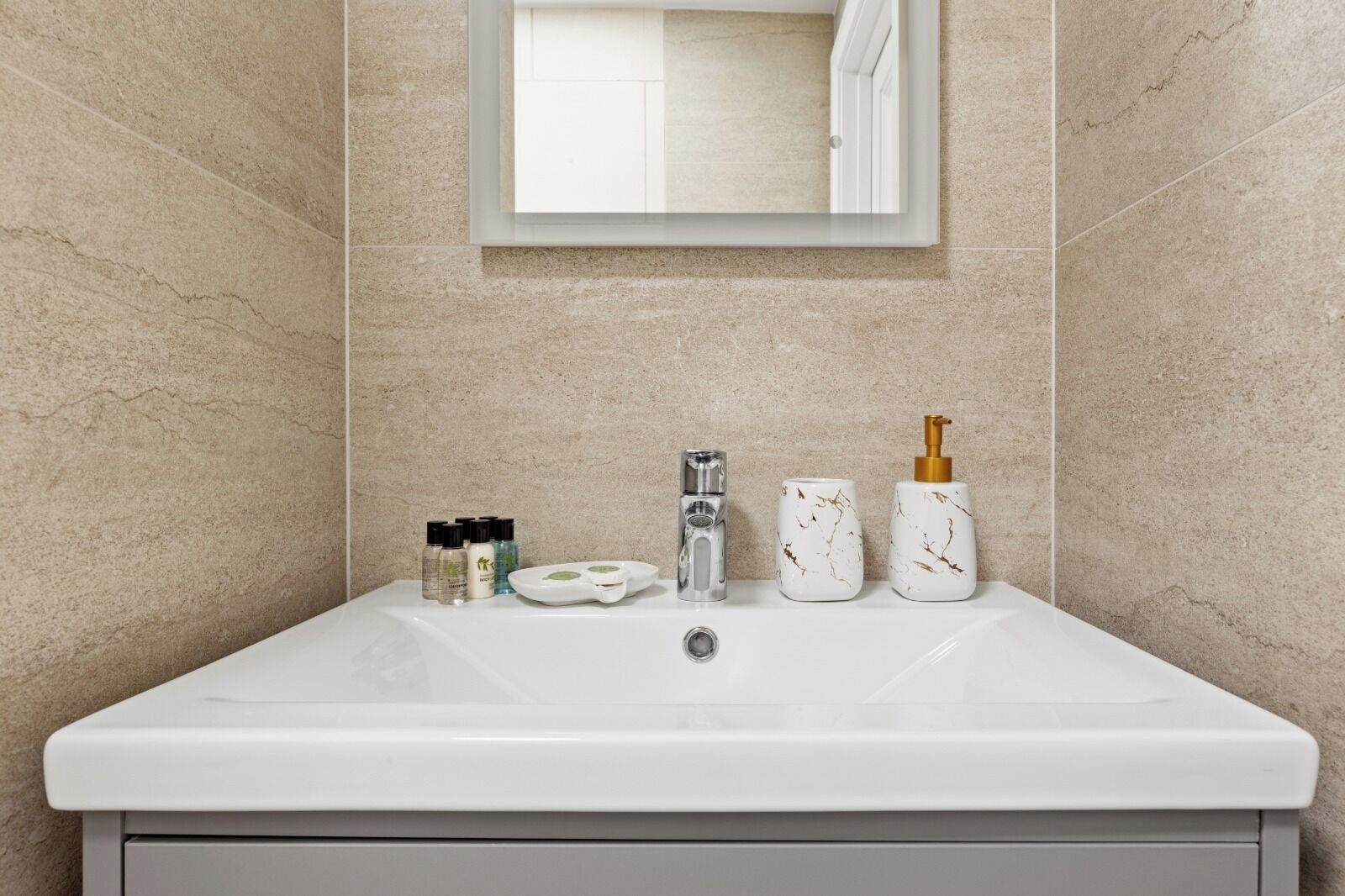 Ein Badezimmer mit Waschbecken, Spiegel und Toilettenartikeln.