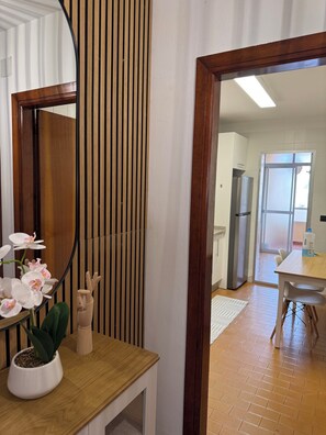 Eine moderne Küche mit einer Holzarbeitsplatte, einem Kühlschrank und Blick durch eine offene Tür.