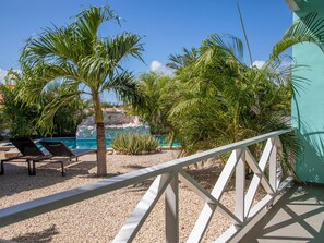 Ein Poolbereich mit Liegestühlen, Palmen und Blick auf eine felsige Landschaft.