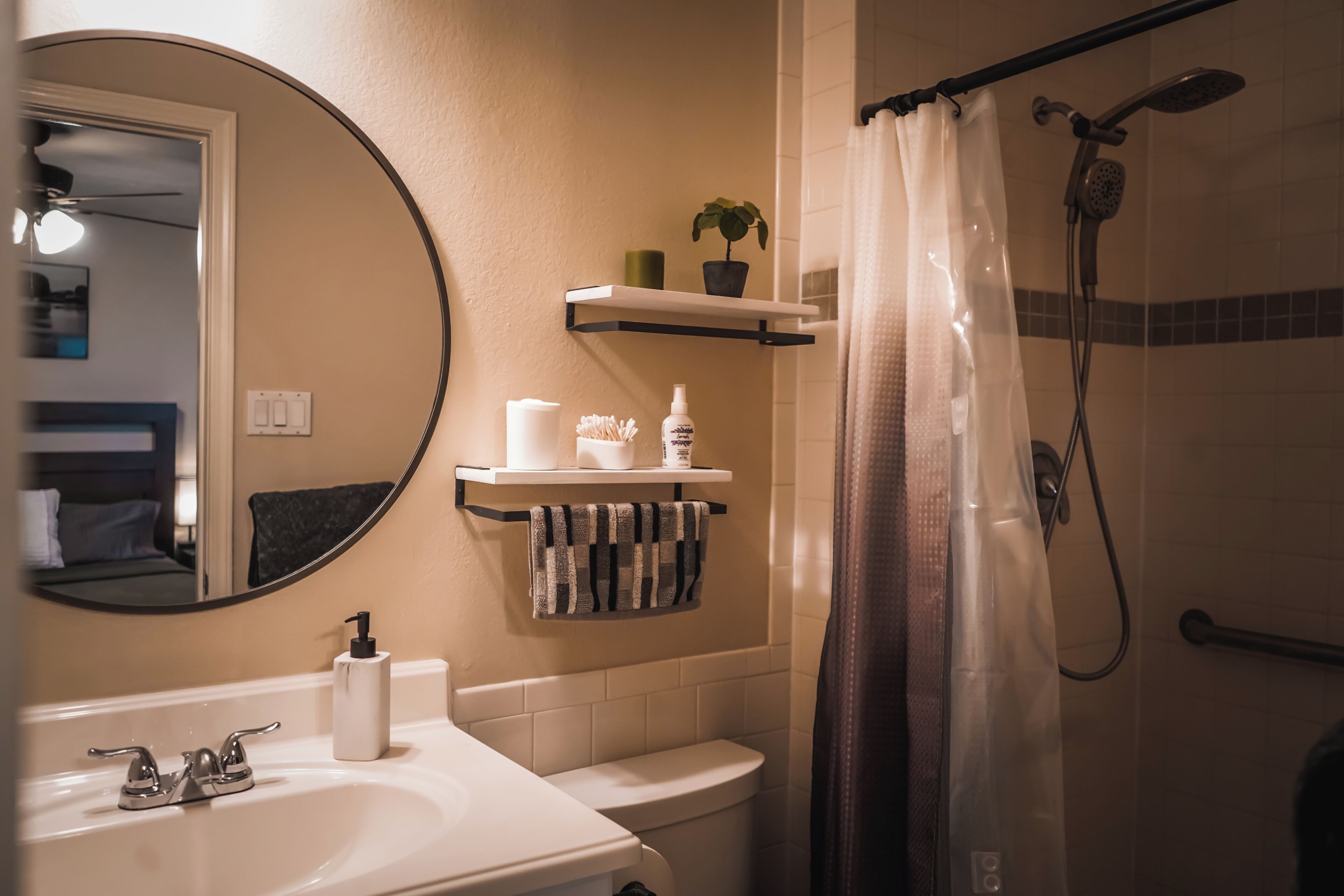 A bathroom with a sink, toilet, shower, and a mirror.