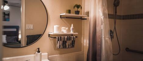 A bathroom with a sink, toilet, shower, and a mirror.